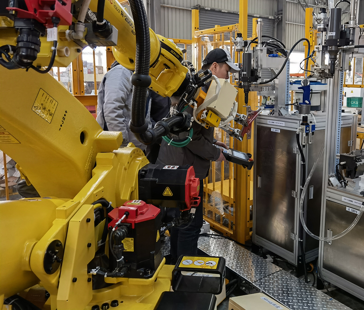 ロボット全自動リベットナットガンの無人化生産ライン。6軸ロボットアームと自動供給キャビネットの現場調整